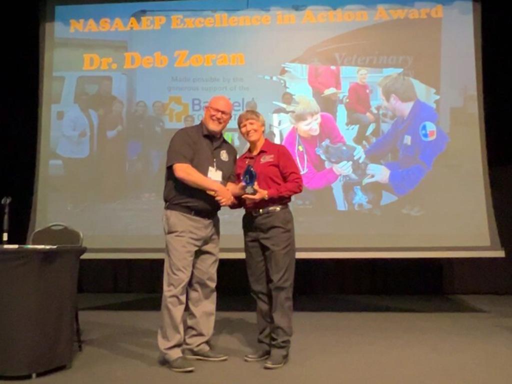 A man handing an award to a woman in a red shirt.