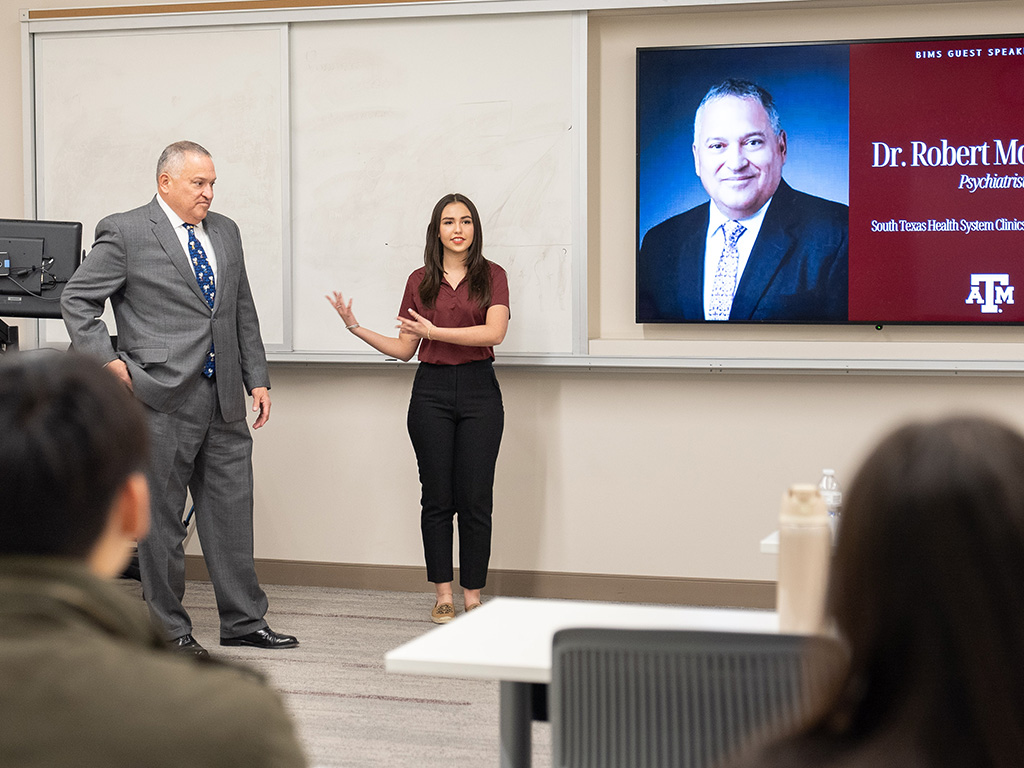 A young woman introduces a guest speaker in her college class.