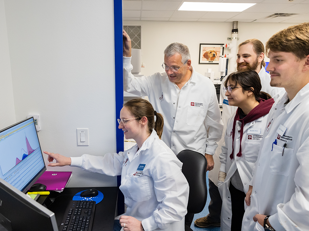 A group of veterinary researchers stand around a computer.