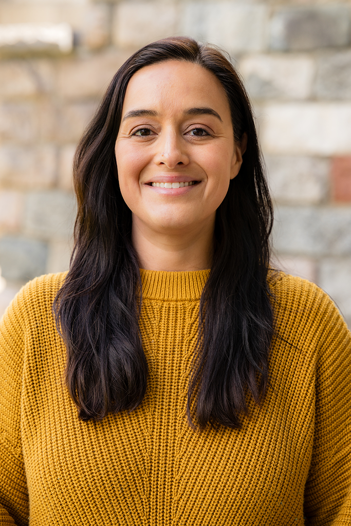 A headshot of a woman with dark hair in a yellow sweater.