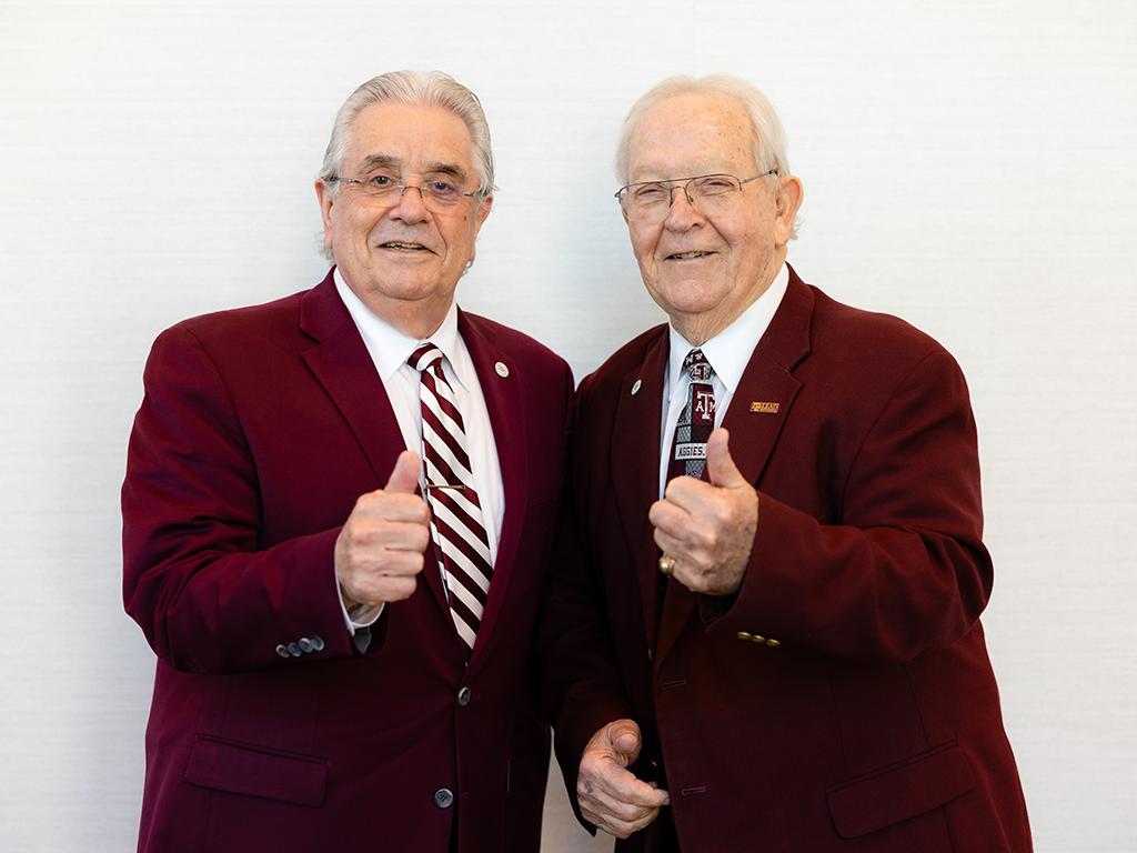 Two men in maroon business suits giving the thumbs-up gesture.
