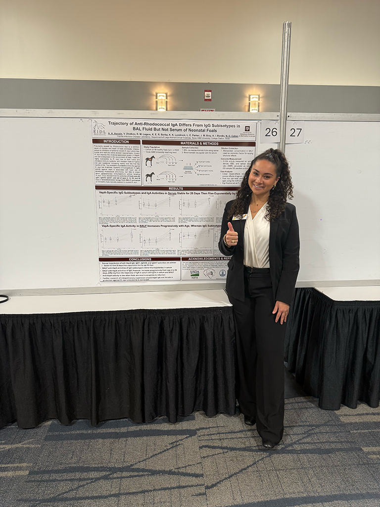 A veterinary student poses with her research poster.