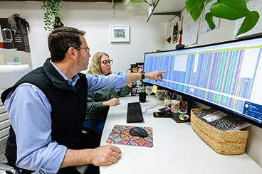Dr. William Murphy and Dr. Nicole Foley view genomic data on a large computer screen.