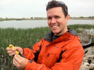 Dr. Jeb Owens holding a small, yellow bird