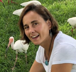 Dr. Sonia Hernandez in a field with several white ibises