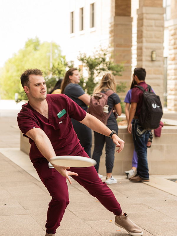 A DVM Student plays frisbee in the Veterinary & Biomedical Education Complex courtyard